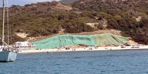 An old illegal landfill emerges from a beach in Sardinia and the municipality covers it with large green sheets